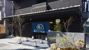 Un bâtiment moderne, orné d’une banderole bleue, avec un arbre et un jardin de rochers.