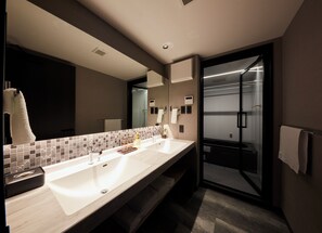 Un baño moderno con un espejo grande, dos lavamanos, un perchero para toallas y una cabina de ducha de vidrio.