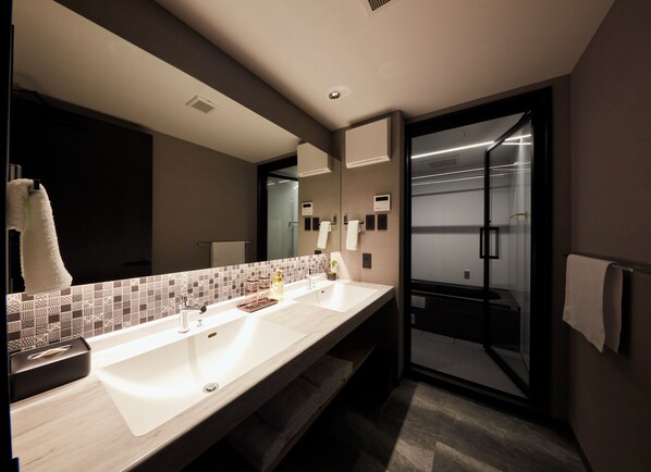 A modern bathroom with a large mirror, two sinks, a towel rack, and a glass shower enclosure.