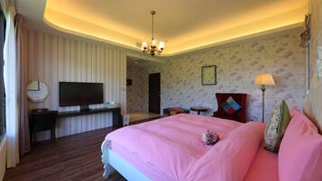 A hotel room with a large bed, a TV, a desk, and a chair.