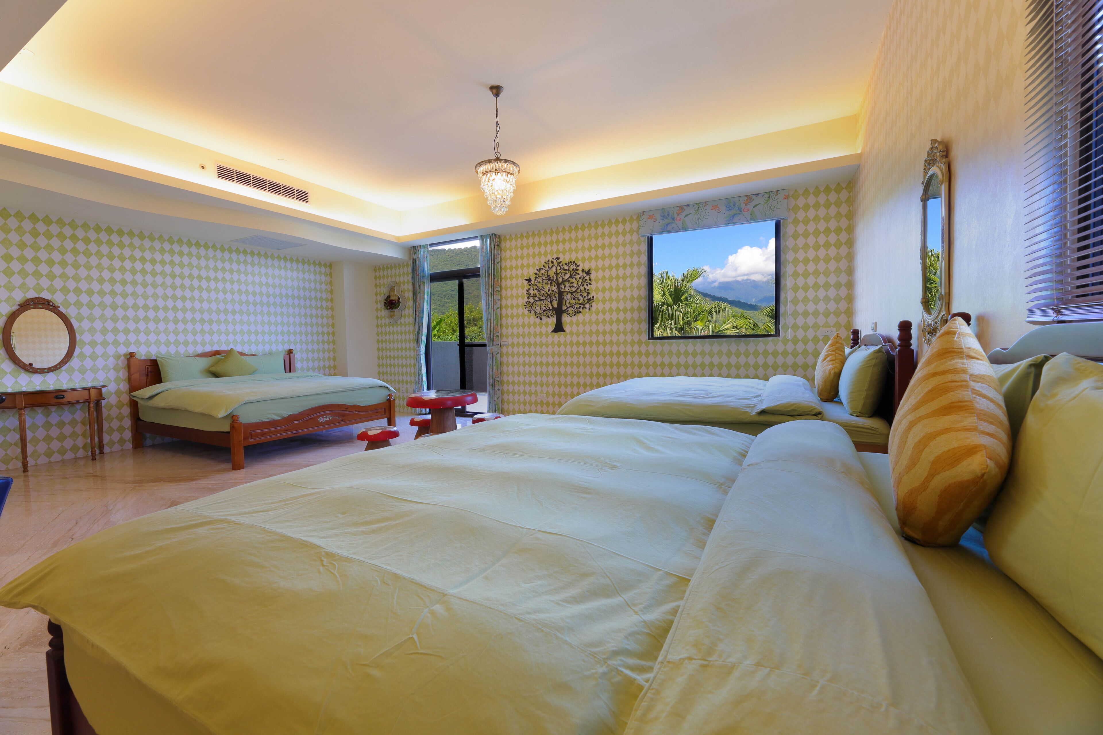 A spacious bedroom with two beds, a wooden nightstand, a mirror, and a window with a view of the outdoors.