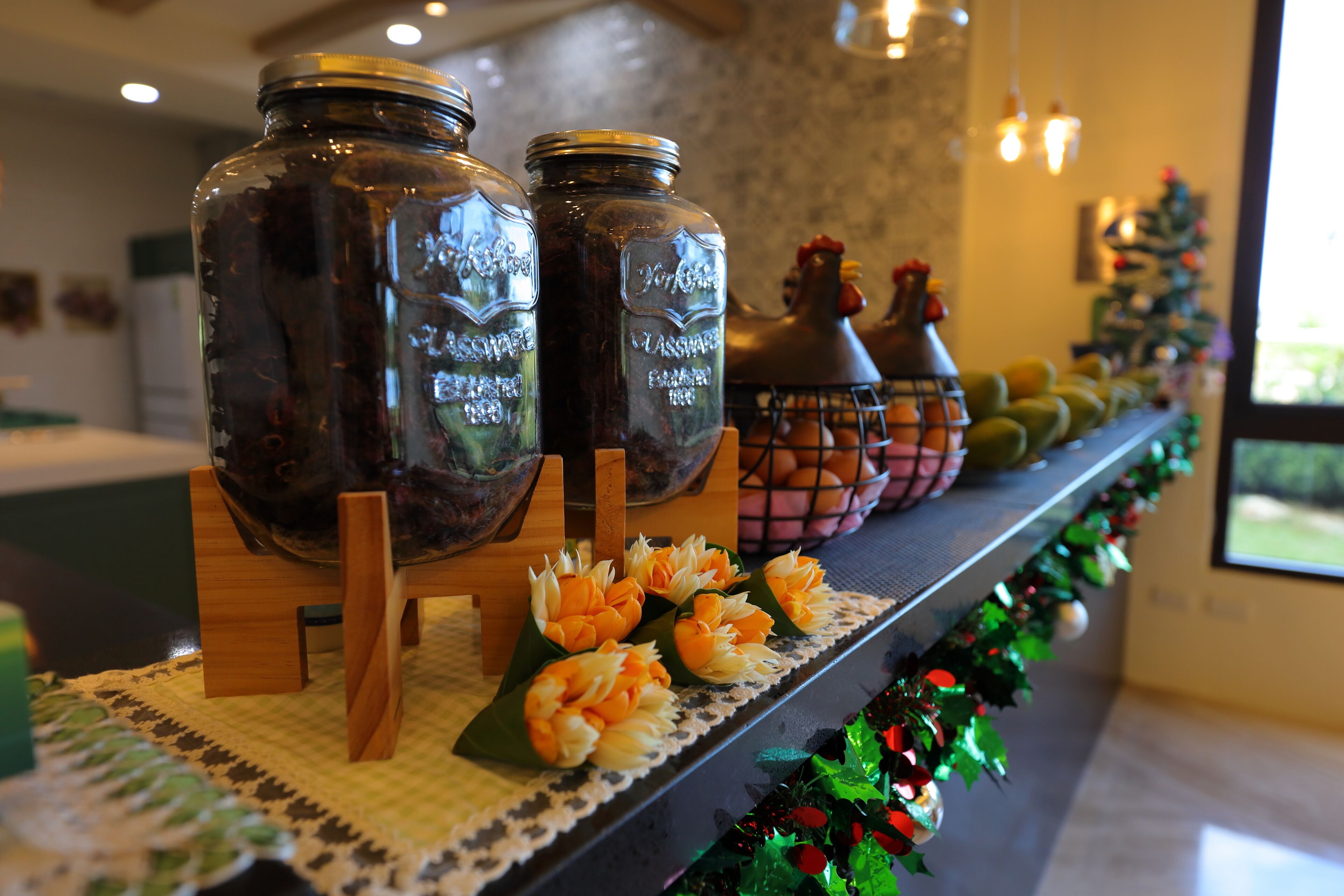 Uma bancada de cozinha com dois potes de vidro, um frango decorativo e um pinheiro de Natal.