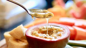 A spoonful of porridge being lifted from a bowl, surrounded by sliced fruits.