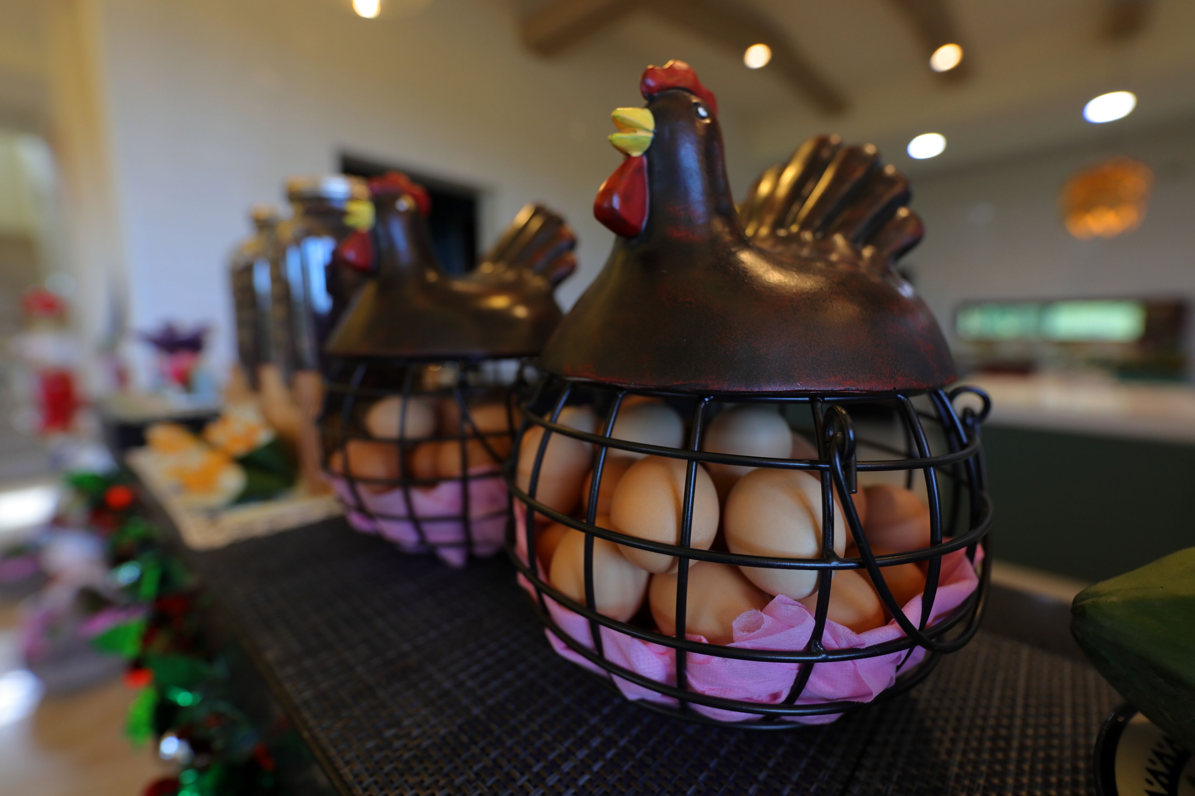 Un coin cuisine avec un plan de travail sur lequel est posé un récipient décoratif en forme de poulet, contenant des œufs.
