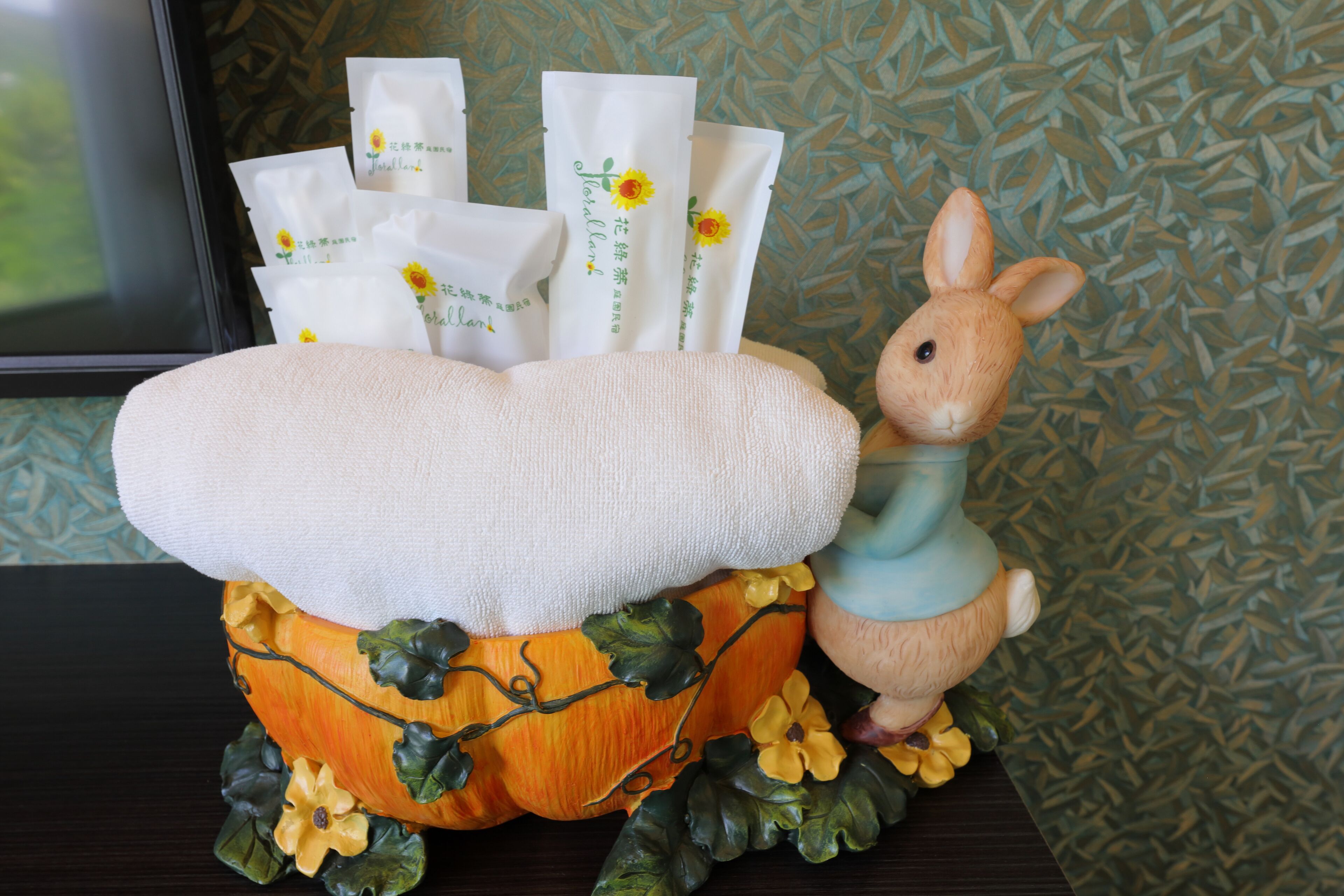 A decorative pumpkin with a plush rabbit and several white packages with text and a sunflower design.