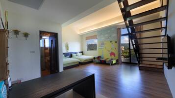 A spacious room with a large bed, a desk, and a staircase leading to an upper level.