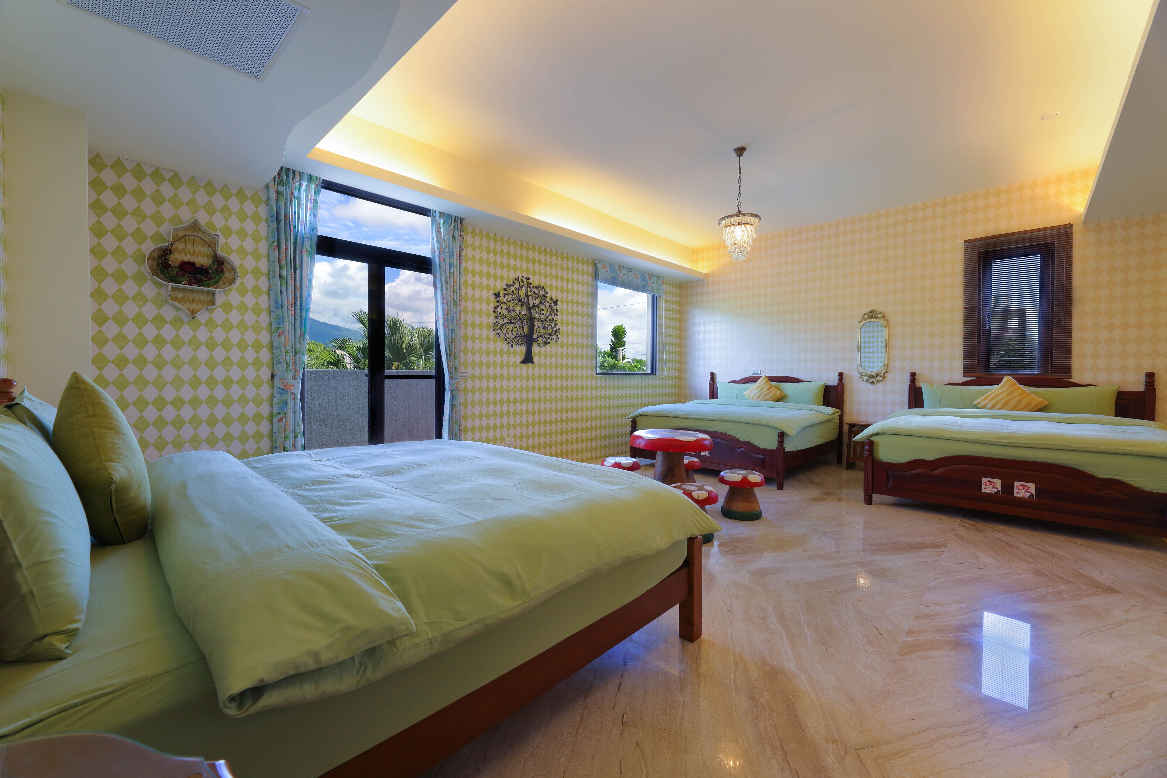 A spacious bedroom with a large bed, two smaller beds, a wooden floor, and a view of the outdoors.