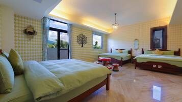 A spacious bedroom with a large bed, two smaller beds, a wooden floor, and a view of the outdoors.