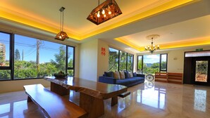 A spacious room with a large wooden table, a blue sofa, and a bicycle. - Floral Land B&B (Shoufeng)