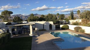 Un espace piscine agrémenté d’une pergola, de coins salon extérieurs et offrant une vue sur les montagnes.
