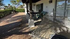 Un patio couvert avec un hamac, du mobilier d’extérieur et une vue sur le paysage environnant.