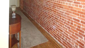 Une pièce avec un mur en briques, un plancher en bois et un luminaire suspendu.