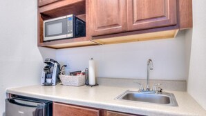 A compact kitchen with a microwave, coffee maker, and sink.