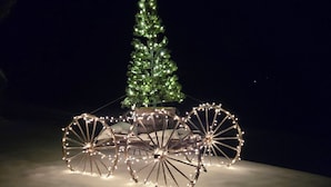 Un suelo cubierto de nieve con un trineo decorado y un árbol de Navidad.