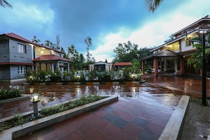 Un patio con suelo de baldosas mojadas, rodeado de edificios con tejados rojos y una zona de estar cubierta.