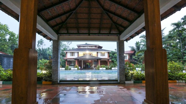 A covered area with a view of a house and pool. - Matthuga (Siddapur)
