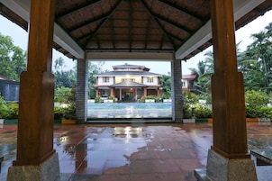 Un espacio cubierto con vista a una casa y piscina.