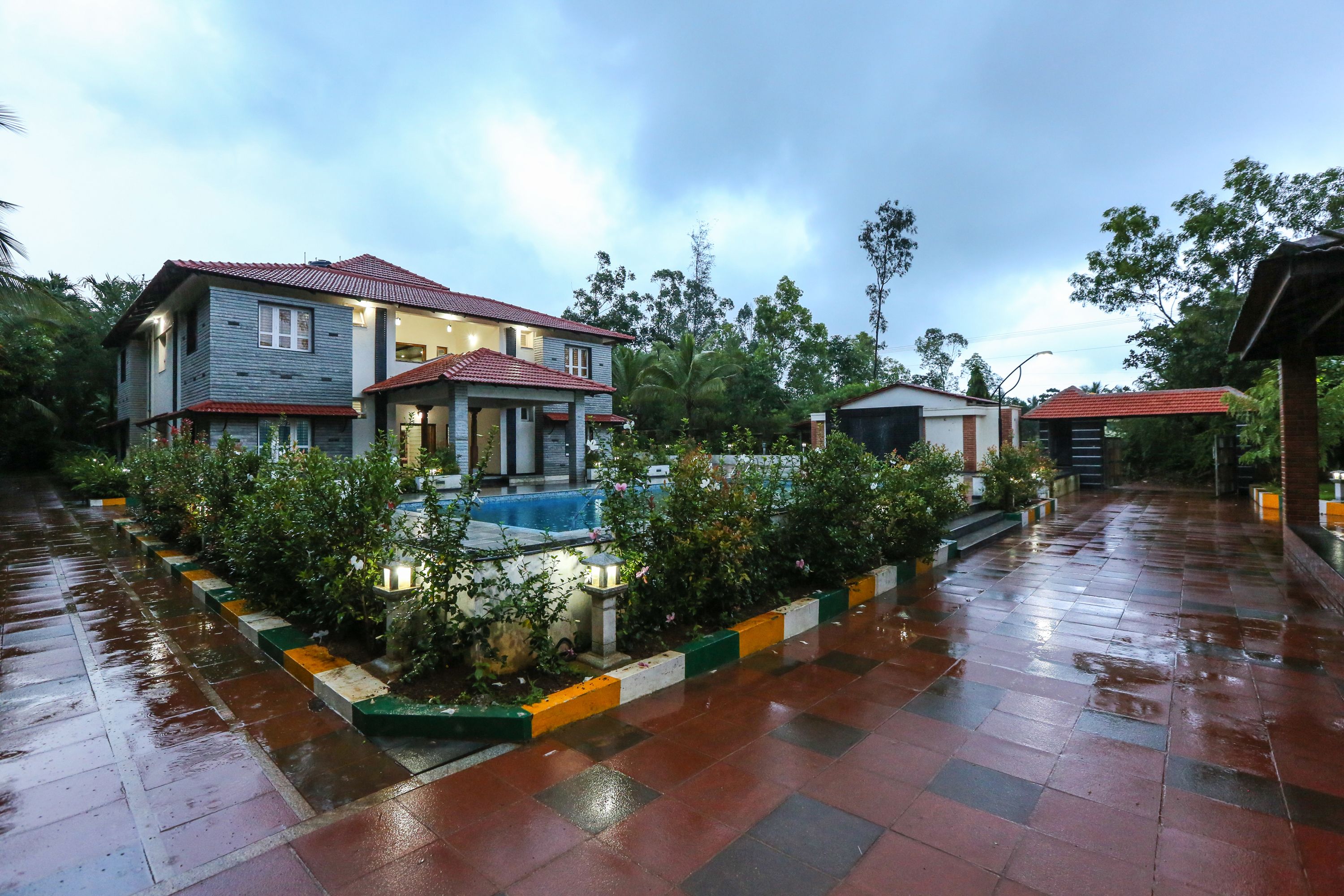 A residential area with a house featuring a tiled roof, a swimming pool, and a well-maintained garden.