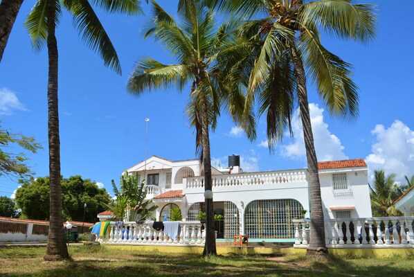 A two-story building with a white facade, large windows, and a balcony.