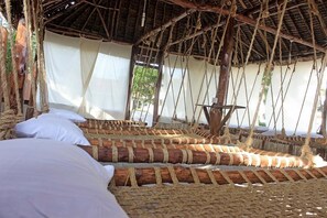 A traditional thatched-roof hut with woven beds and a simple, rustic interior.