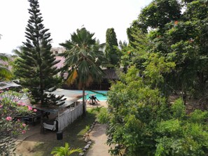 A pool area surrounded by lush greenery, including palm trees and various shrubs.