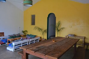 A room with a wooden table, benches, and colorful cushions.