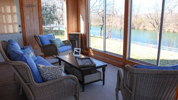 Une pièce chaleureuse, meublée de meubles en osier, avec une table et une vue sur un lac.