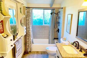 Een bad/douchecombinatie, een haardroger, handdoeken, zeep