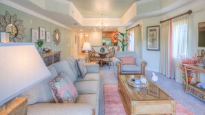 A spacious living room with a sofa set, a coffee table, and a dining area with chairs and a table.
