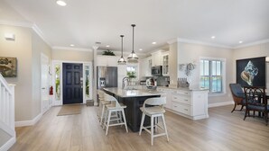 A spacious kitchen with a central island, white cabinetry, and a dining area with a view. - Waterfront Luxury Villa (62) with sunset views and boat slip (Marathon)