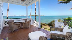 A covered outdoor area with wicker furniture, a table, and a view of the sea. - Waterfront Luxury Villa (62) with sunset views and boat slip (Marathon)