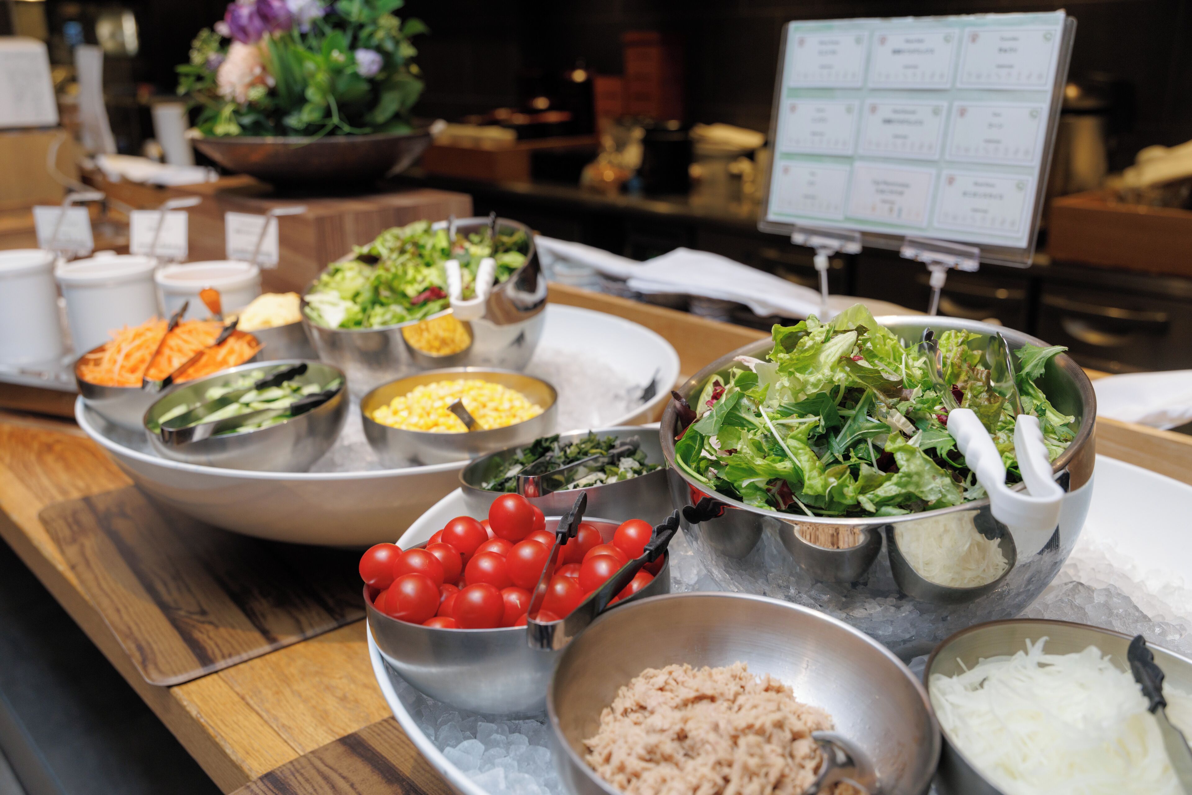 A buffet with various food items including salads, vegetables, and a bowl of cherry tomatoes.