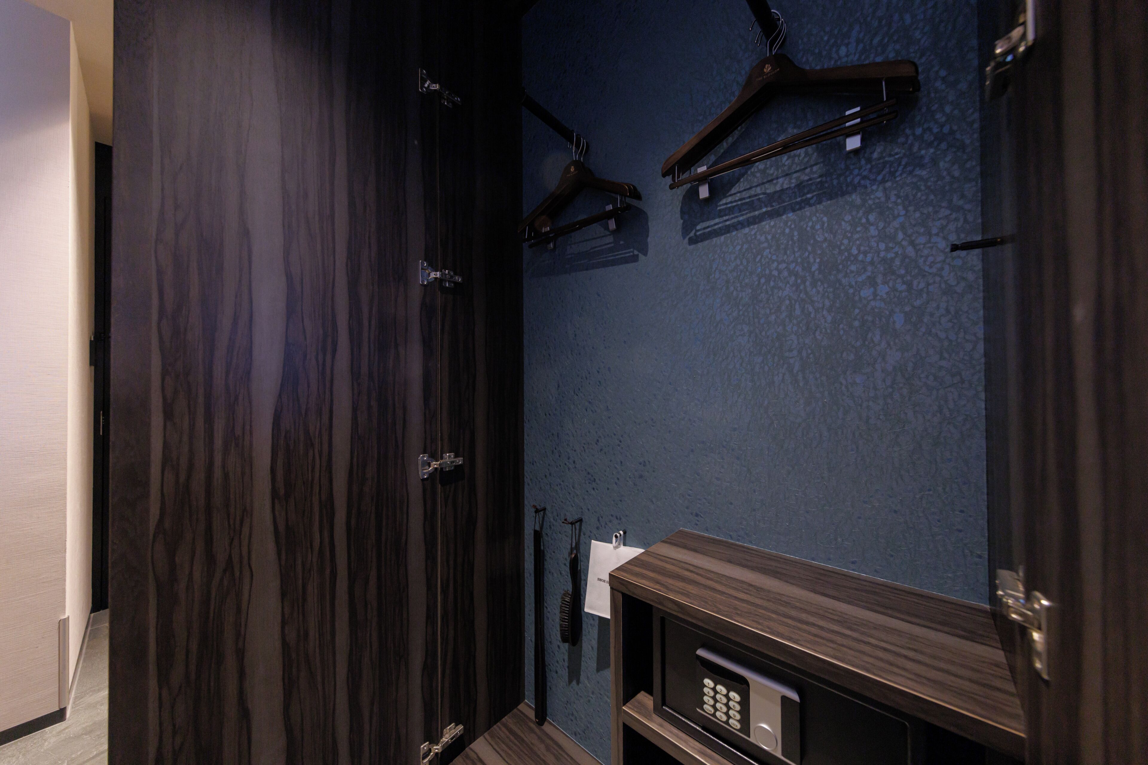Ein Badezimmer mit dunklen Holzschränken, einer blauen, strukturierten Wand und einer eingebauten Mikrowelle.