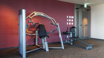 Ein Fitnessraum mit Trainingsgeräten, einer Bank und einem an der Wand befestigten Schild.