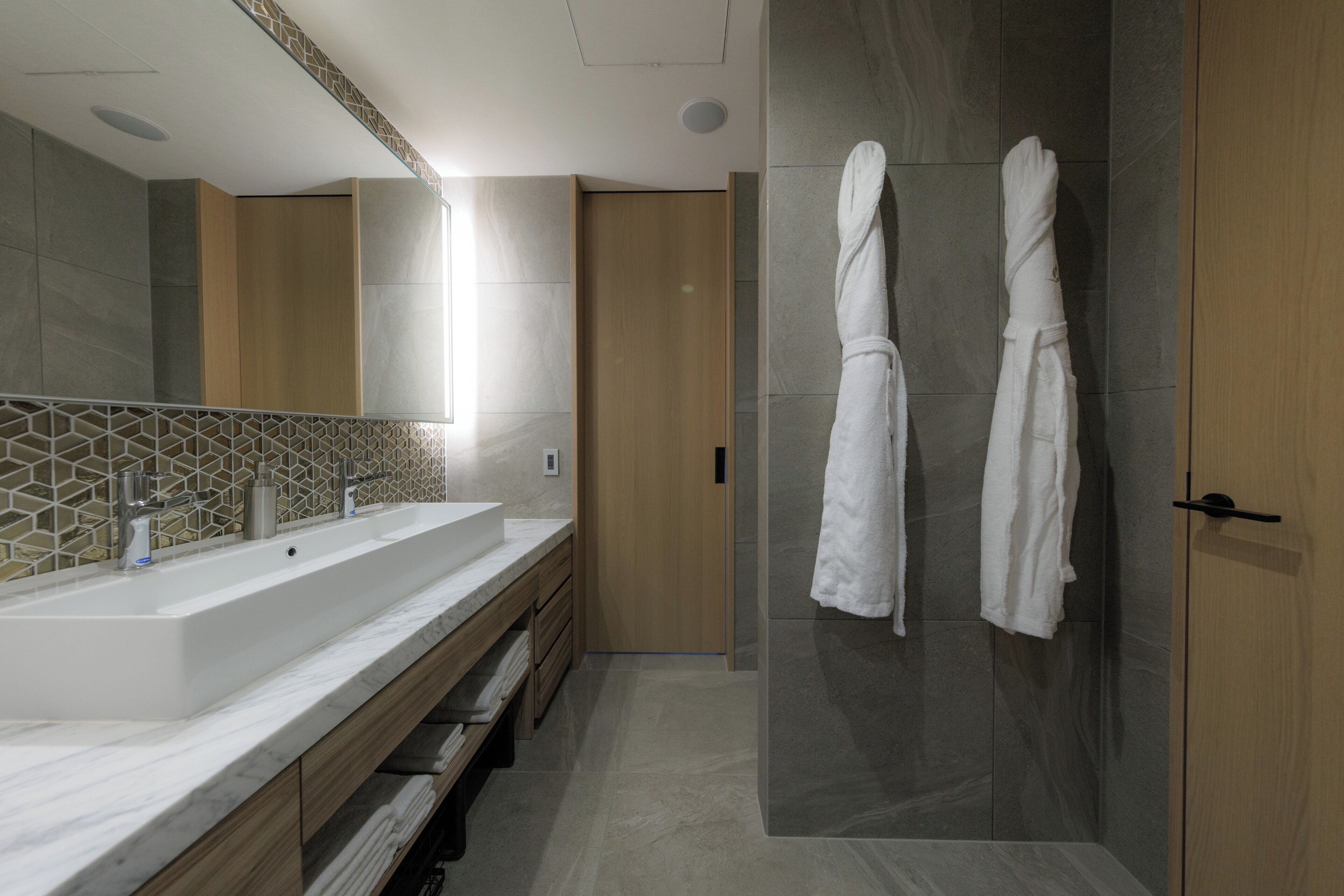 A modern bathroom with a large sink, mirror, and two white towels hanging on a wall.