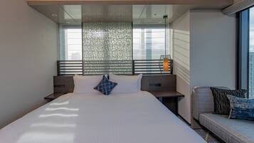 A modern hotel room with a large bed, a seating area, and a view of the city.