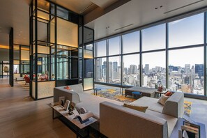 A spacious lobby with a large window offering a city view, modern furniture, and a reception desk.