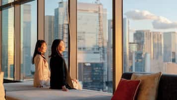 Two individuals seated on a balcony with a cityscape view.