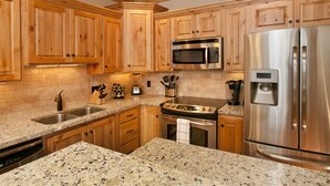 A kitchen with wooden cabinets, granite countertops, stainless steel appliances, and a built-in oven. - Teton Springs Condo #206 in Victor w/ A/C, W/D, WiFi, Balcony, Grill & Garage (Victor)
