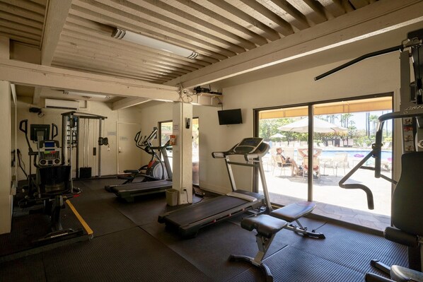 Une salle de sport équipée de tapis de course, de vélos elliptiques et de matériel de musculation.