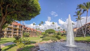Un hôtel doté d’une piscine, de palmiers et d’une fontaine.