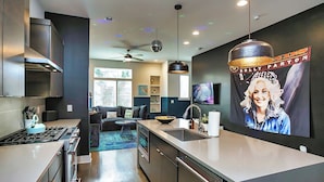 A modern kitchen with a central island, built-in appliances, and a dining area with a sofa and coffee table. - 🏙️ Views 🌆 from Spectacular Rooftop | 🔥Fire Pit | Bach Groups!💃🏼🕺🏼 (Nashville)