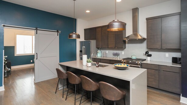 A modern kitchen with a central island, bar stools, pendant lighting, and dark cabinetry. - 🏙️ Views 🌆 from Spectacular Rooftop | 🔥Fire Pit | Bach Groups!💃🏼🕺🏼 (Nashville)