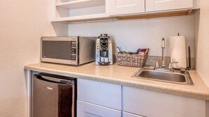 Una cocina compacta con microondas, cafetera y lavabo.