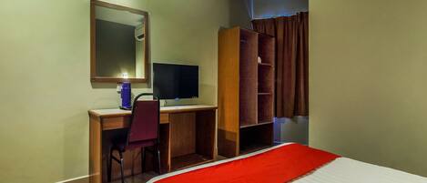 Una habitación de hotel con una cama, un escritorio con computadora, una silla, un armario y un espejo.