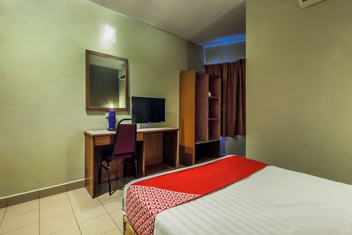 Una habitación de hotel con cama, escritorio, silla y armario.