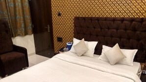 Une chambre d’hôtel avec un grand lit, une tête de lit marron et un fauteuil marron.
