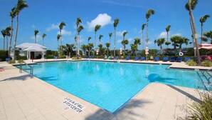 A swimming pool with a 3ft 6in at wall 5ft center depth, surrounded by palm trees and lounge chairs. - Marathon Townhome | Boat Slip + Pool | Gulf Access (Marathon)