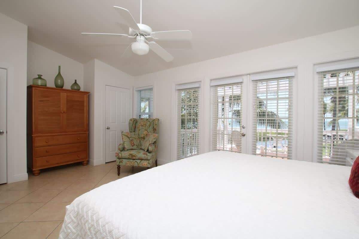 Une chambre à coucher avec un grand lit, une armoire en bois, une chaise et un ventilateur de plafond.