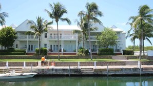 A waterfront property with a large white building featuring multiple balconies and a dock. - Marathon Townhome | Boat Slip + Pool | Gulf Access (Marathon)